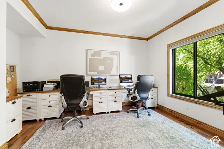 Dedicated office space featuring expansive wood-finish flooring, white walls, and wood trim accents