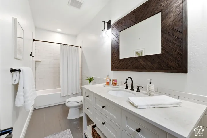 Bathroom featuring a white vanity with integrated sink, a large wood-framed mirror with a chevron pattern, and dark bronze fixtures