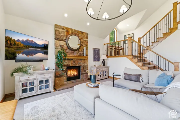 Living area featuring a stone-clad fireplace with a wood mantel, a multi-level staircase with wood railings and wrought iron balusters, and recessed lighting