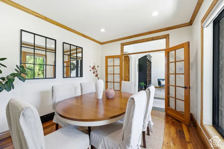 Dining area featuring wood-finish flooring, white walls, and natural wood trim