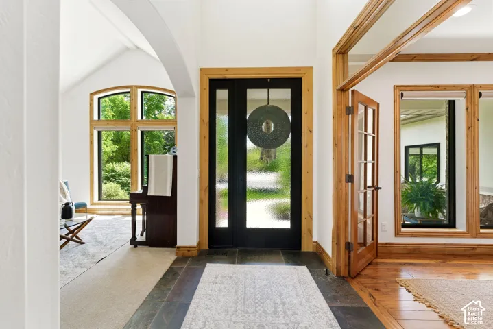 Entry foyer featuring slate tile flooring, a dark-paneled door with frosted glass inserts, and natural wood trim throughout