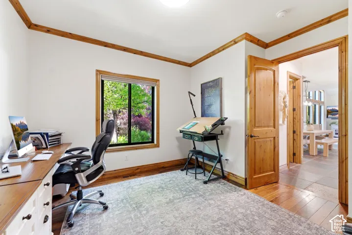 Room featuring hardwood flooring, white walls, natural wood trim, a single window, and a wood-paneled door