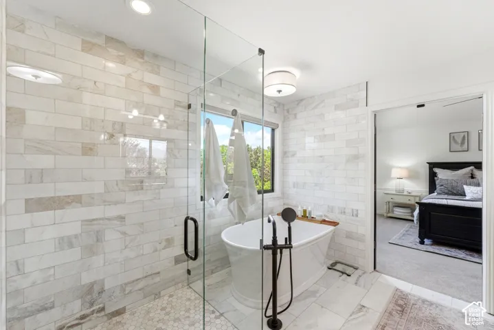 Bathroom featuring a glass-enclosed shower, a freestanding soaking tub with floor-mounted fixtures, and extensive subway tile walls