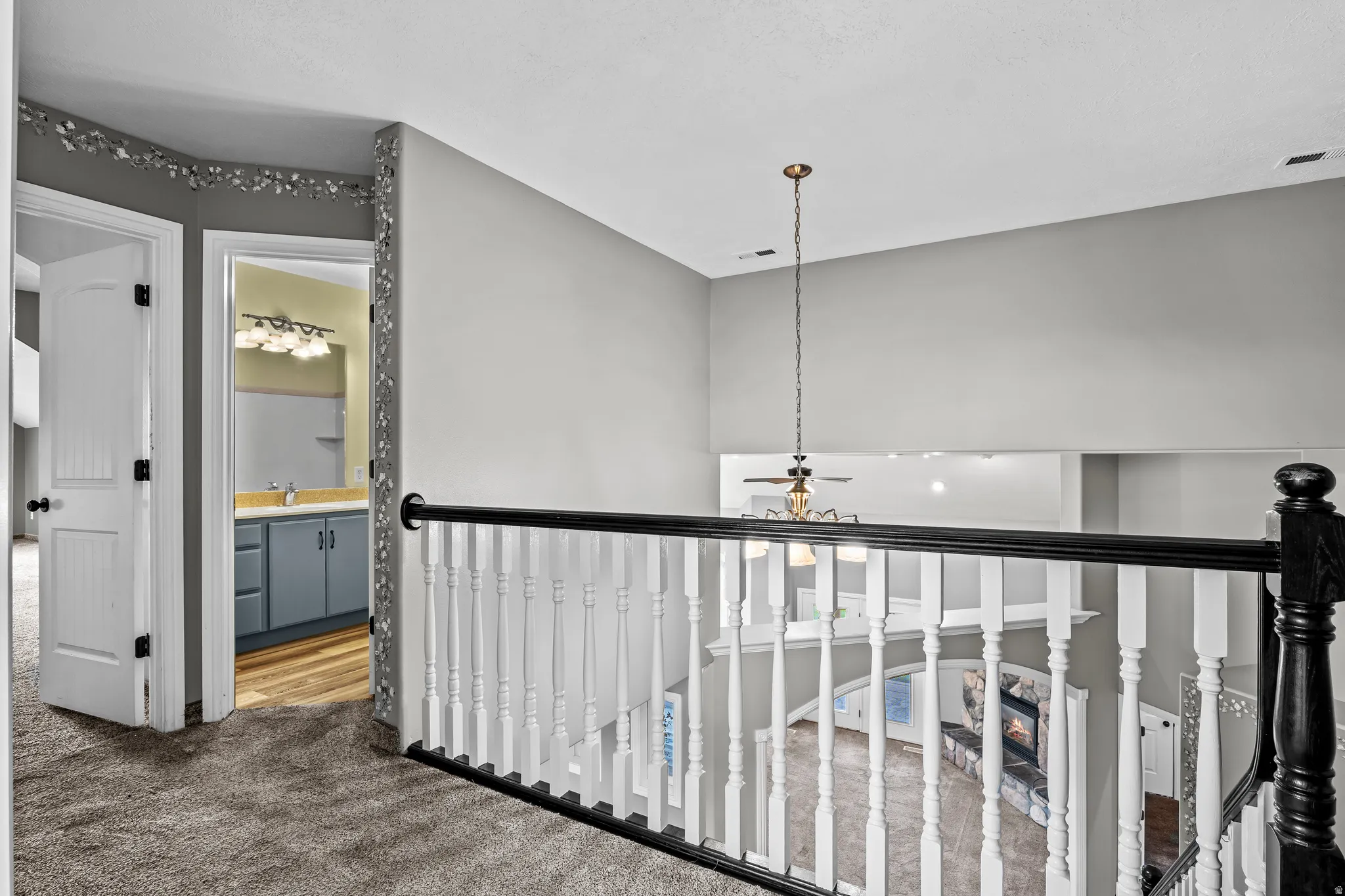 Carpeted hallway with white interior doors, a decorative wall border, and a black and white staircase railing