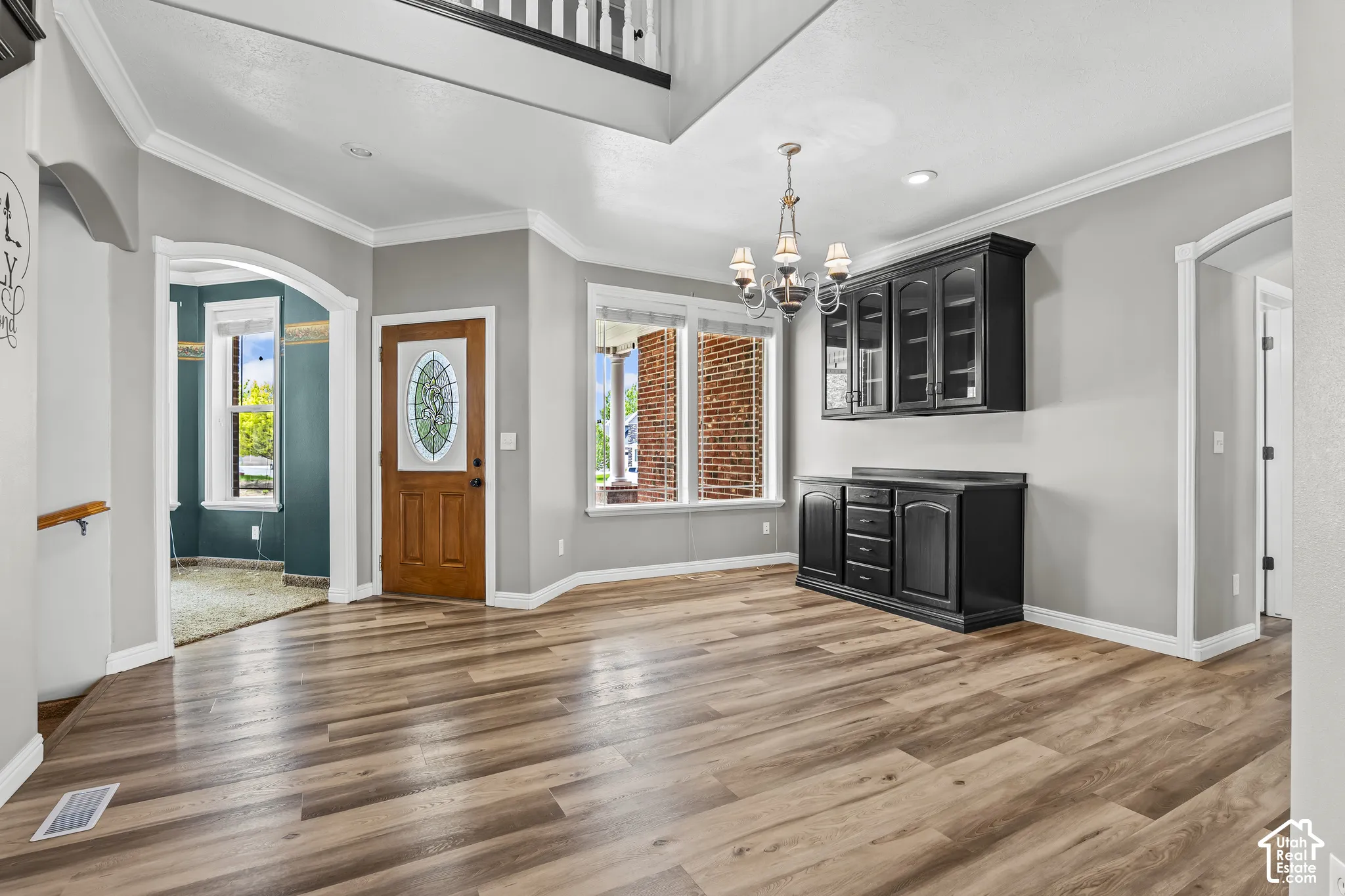 Spacious foyer entry with wood-finish flooring, a decorative oval glass front door, and a built-in black cabinetry unit