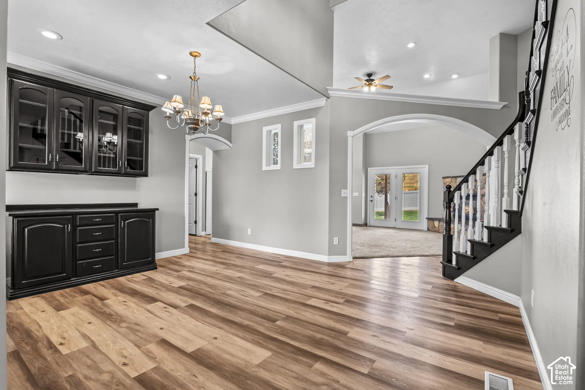 Spacious interior featuring wood-finish flooring, a built-in black cabinetry unit with glass fronts, and a decorative chandelier
