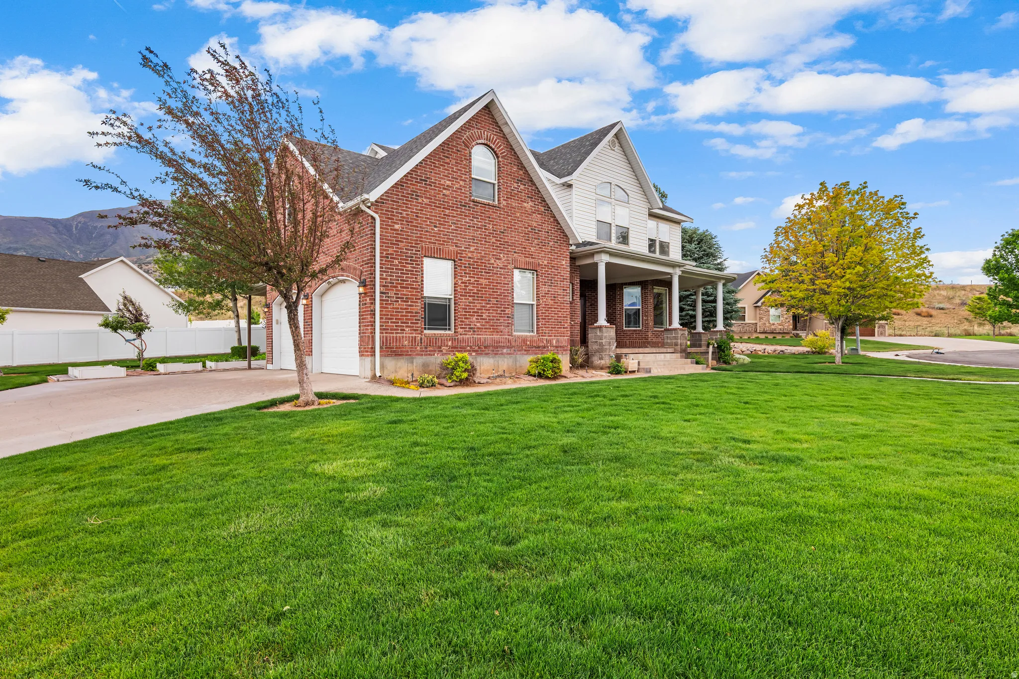 Brick and siding exterior featuring a covered front porch with stone pillars
