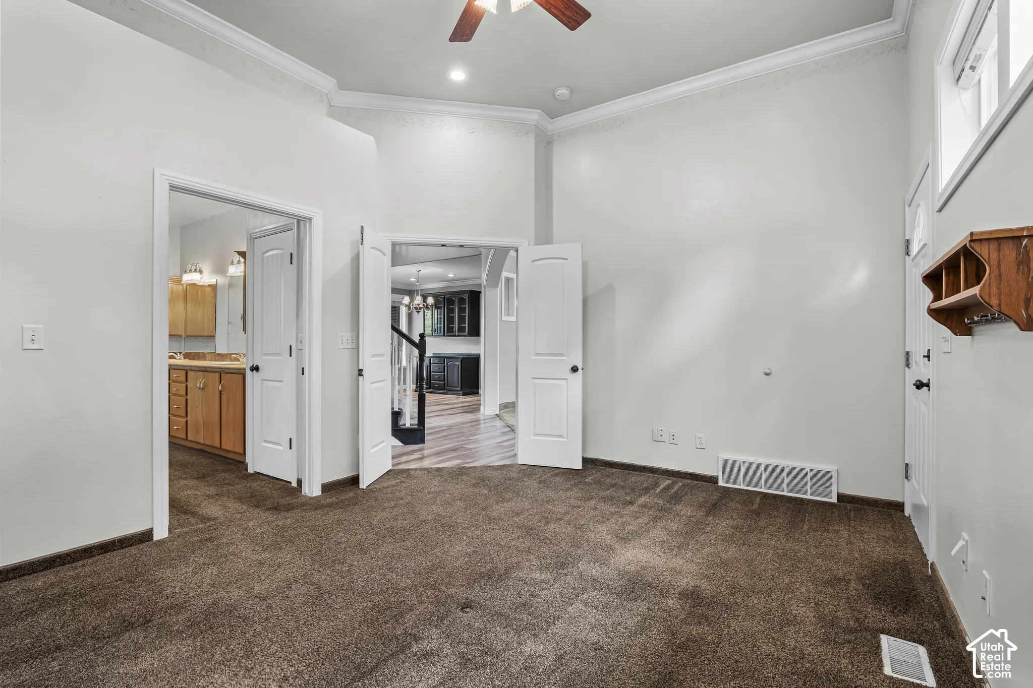 Carpeted room featuring high ceilings, white crown molding, and recessed lighting