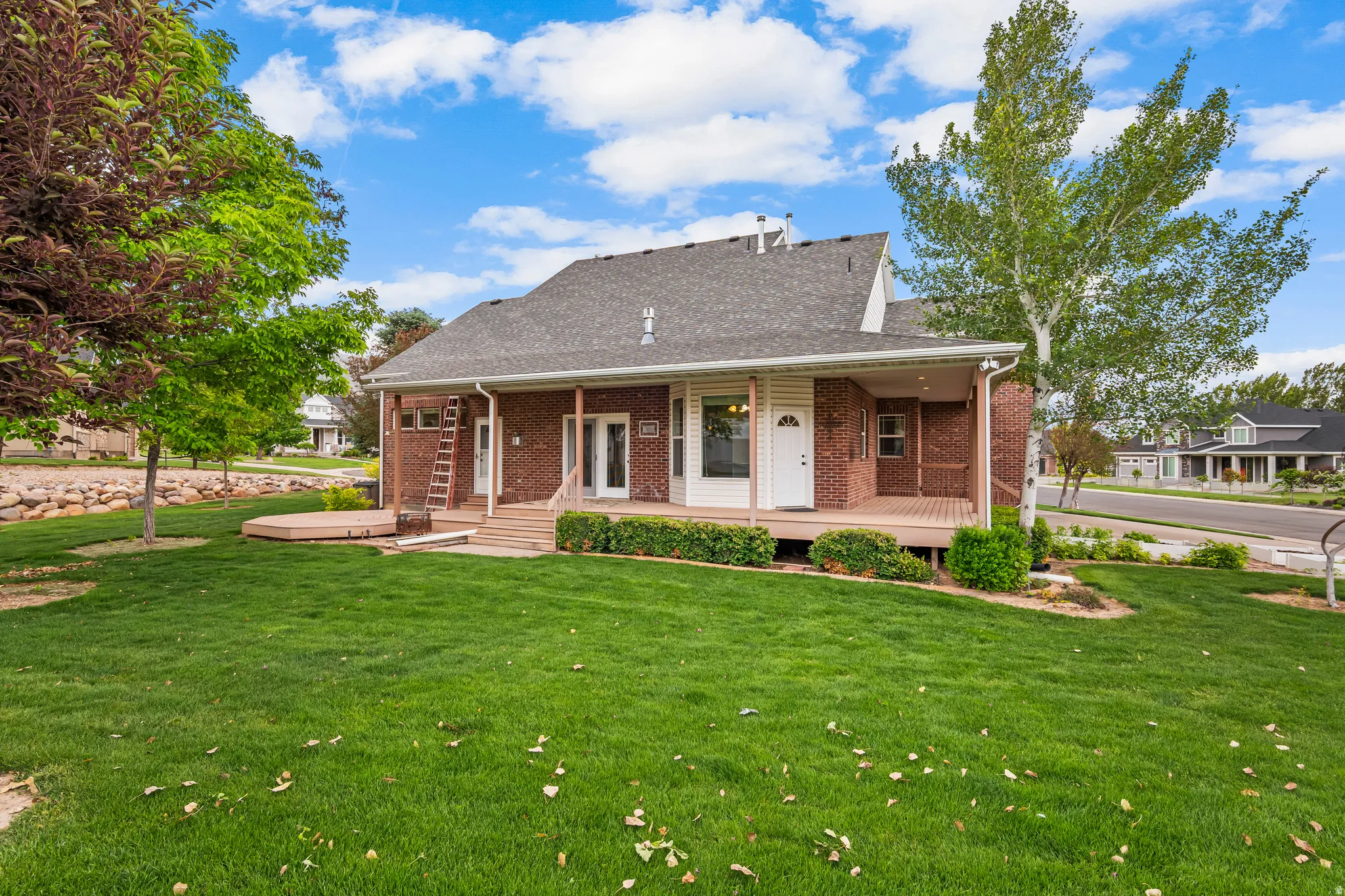 Rear exterior with brick facade and a covered wood deck
