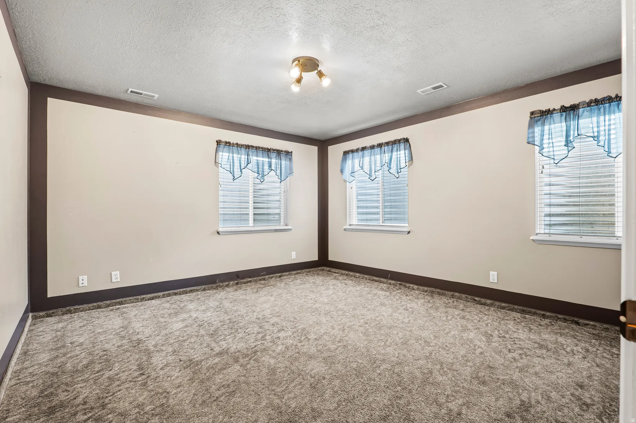 Carpeted room with multiple windows featuring blinds