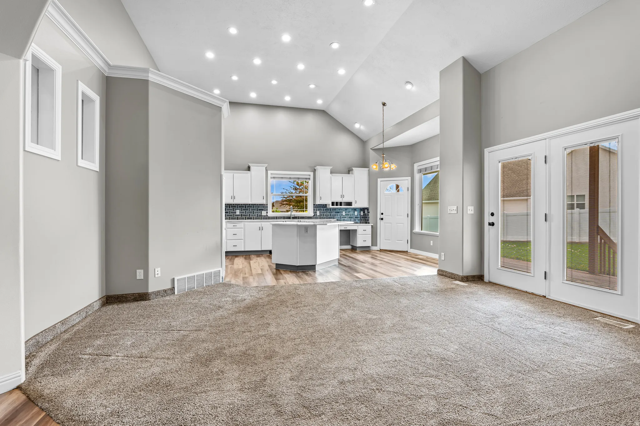 Spacious living area featuring vaulted ceilings, recessed lighting, and soft gray carpeting