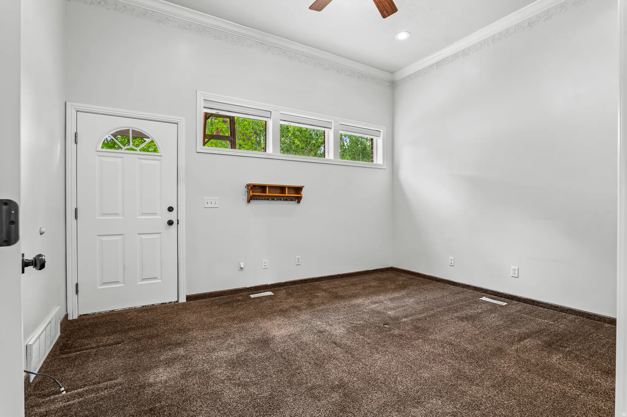 White paneled entry door with an arched glass insert, accompanied by a transom window array