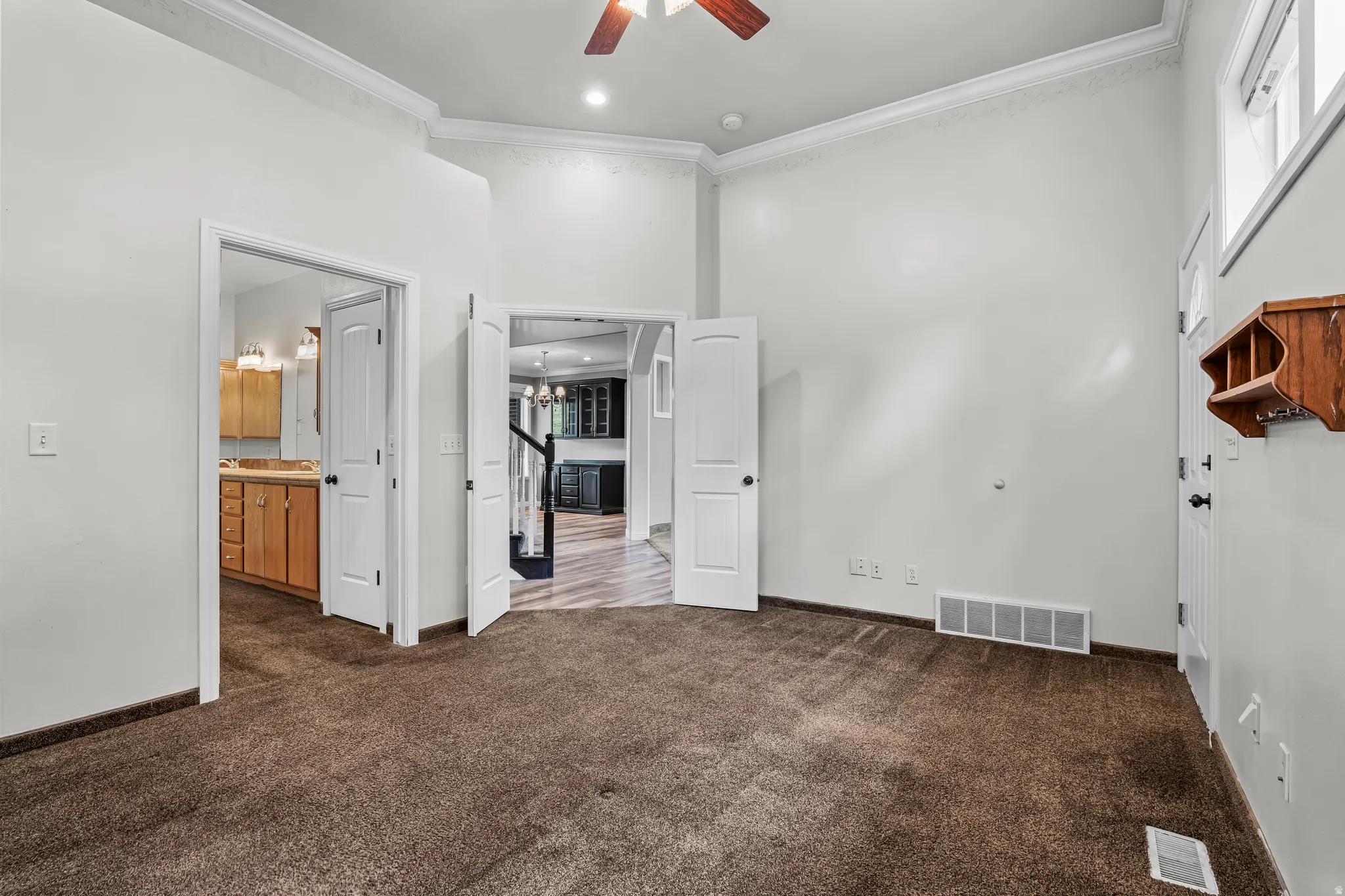 Carpeted room featuring high ceilings, white crown molding, and recessed lighting