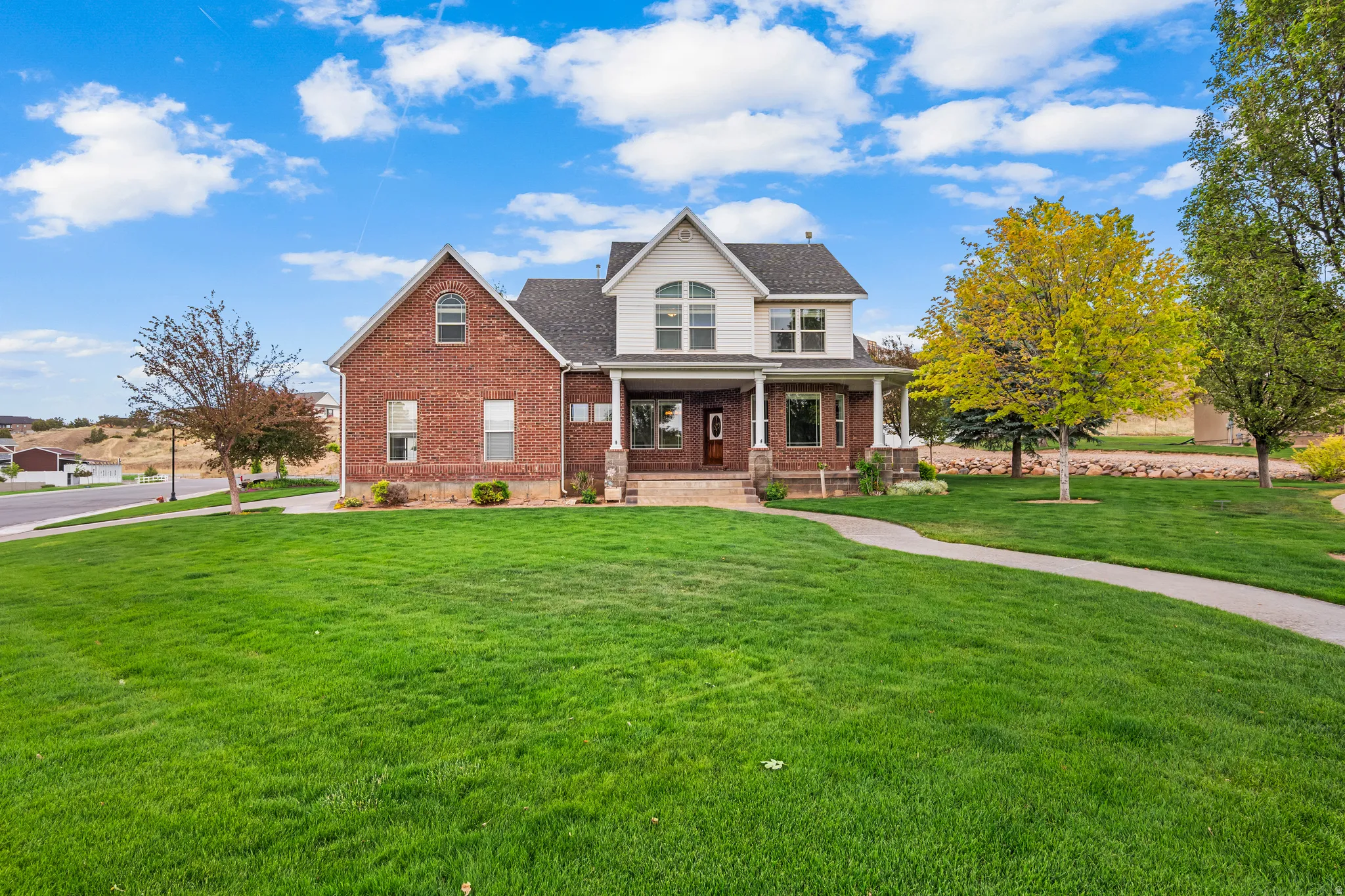 Brick and siding exterior featuring a covered front porch with white columns