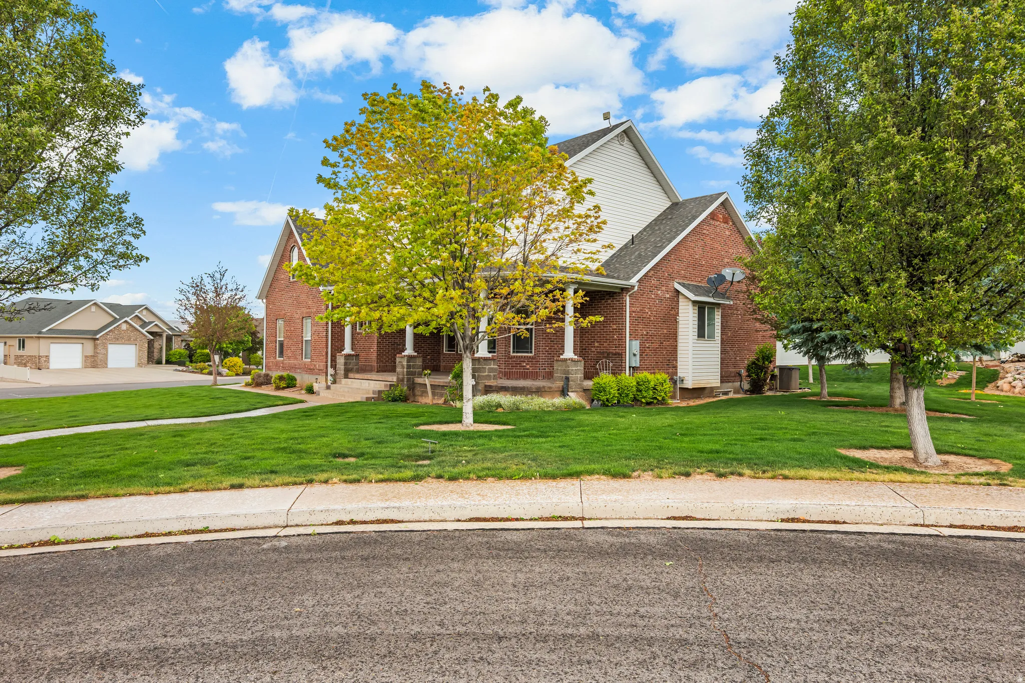 Traditional brick home with white siding accents and a covered front porch featuring column supports