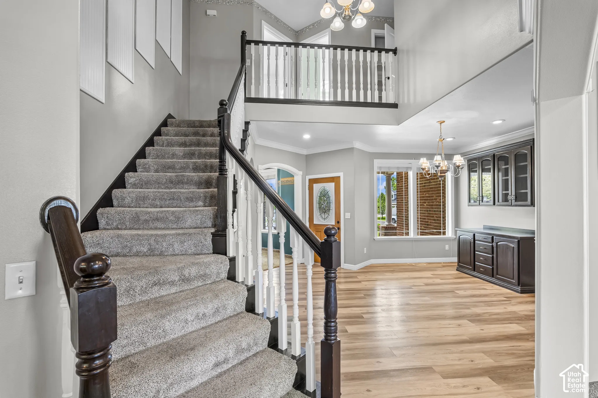 Carpeted staircase with dark wood handrail and white balusters