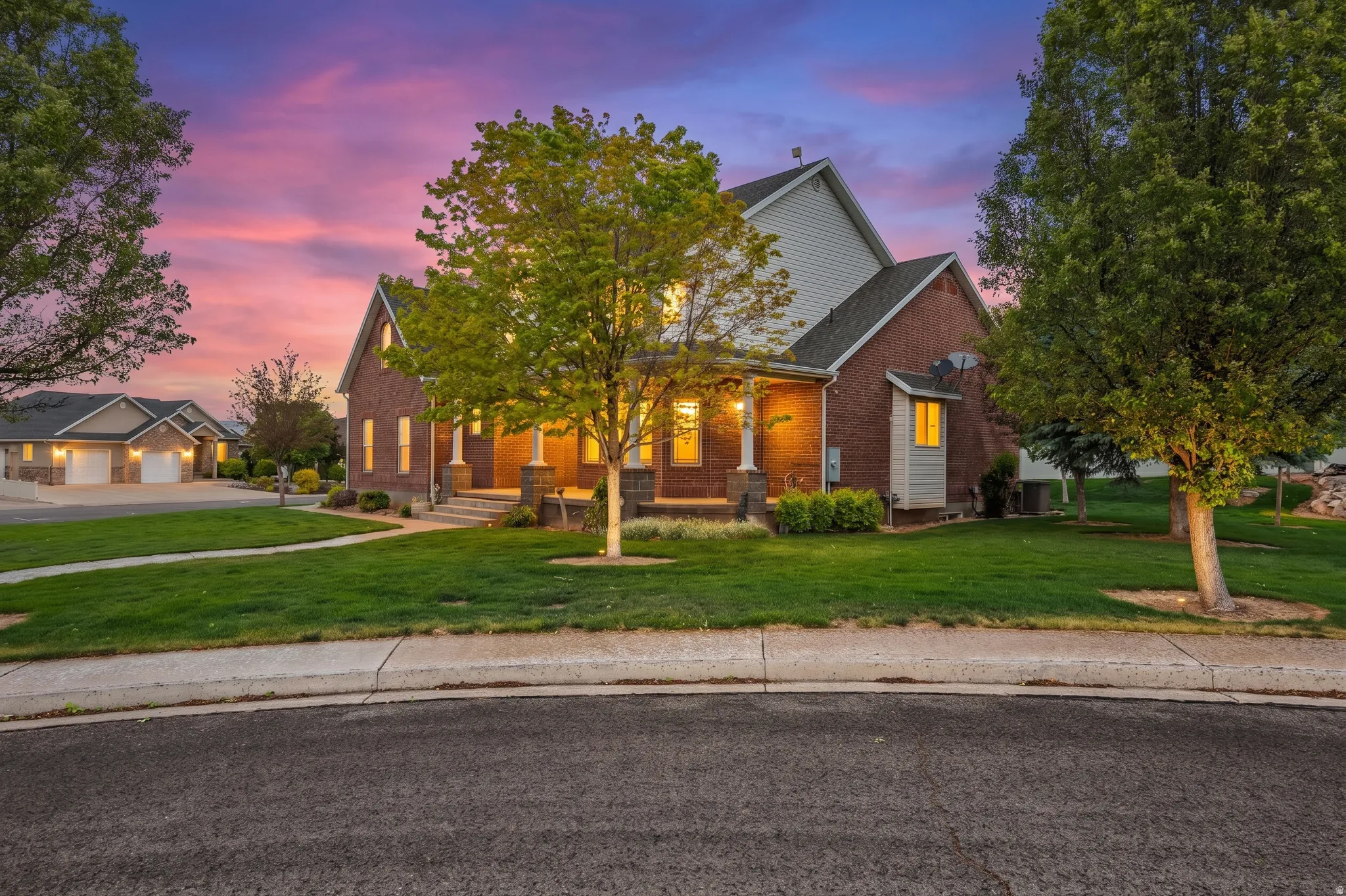 Brick exterior with a gabled roofline, columned front porch, and manicured front lawn