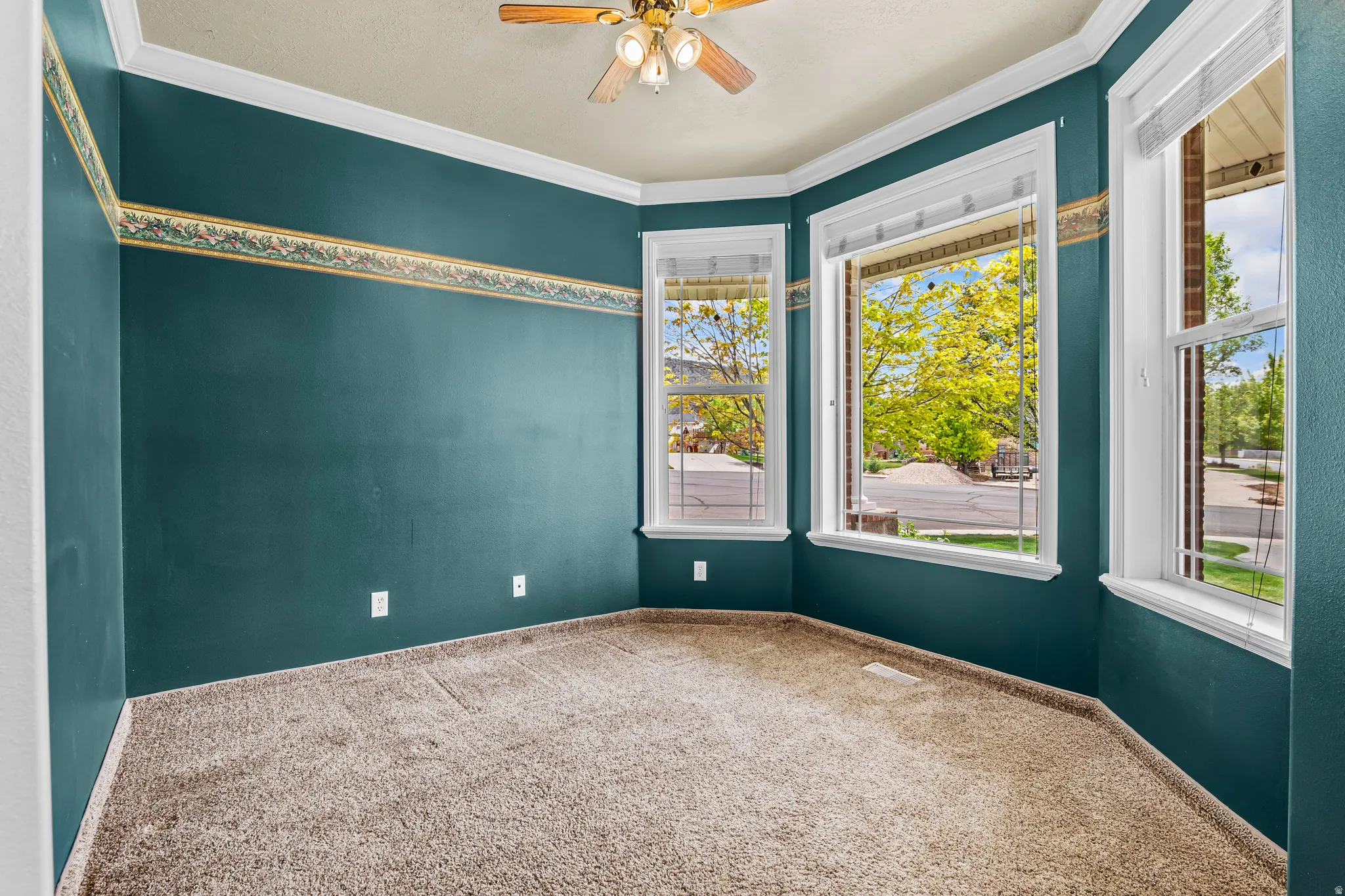 Room featuring a bay window, wall-to-wall carpeting, and a ceiling fan with integrated lighting