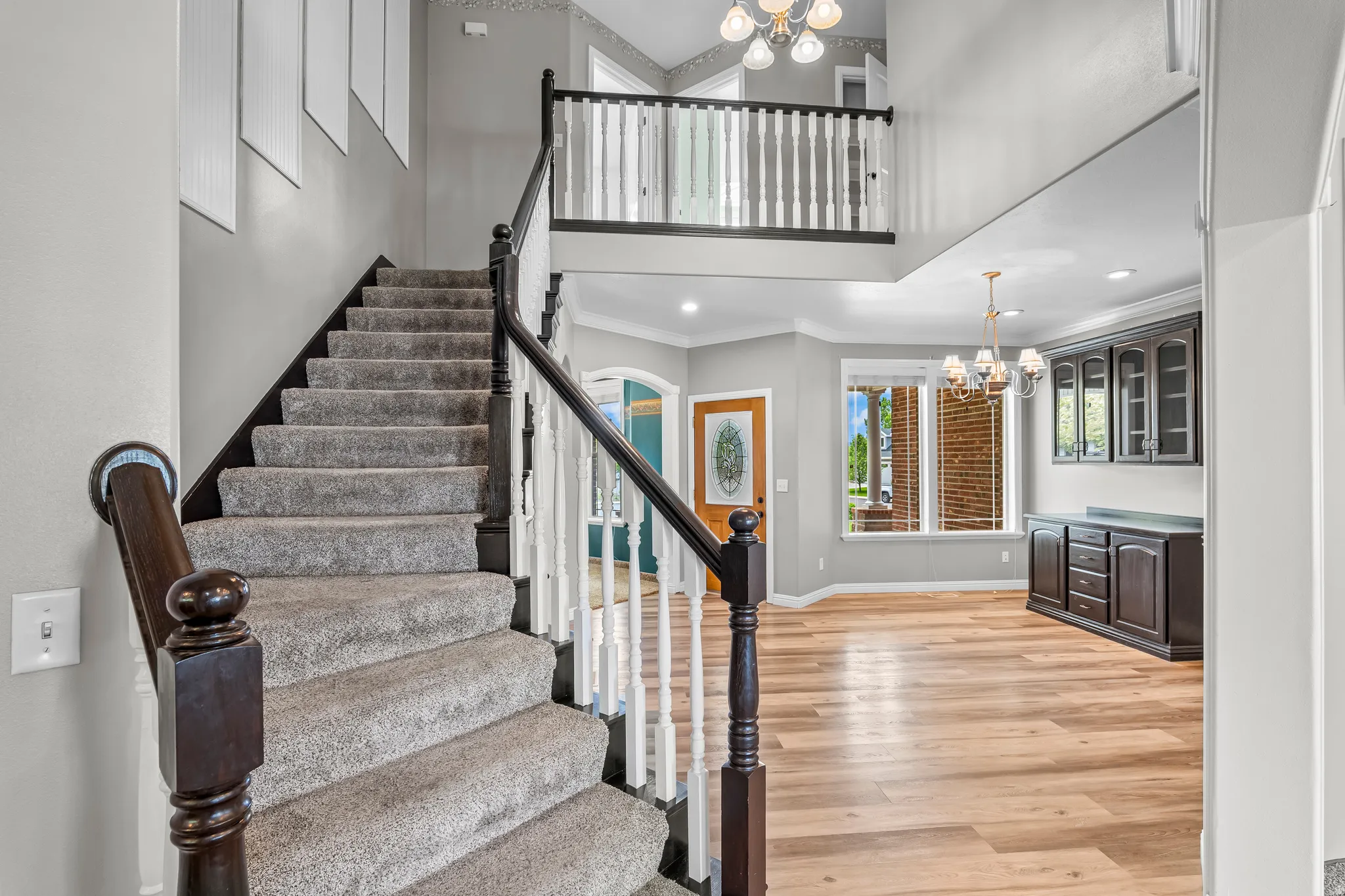 Carpeted staircase with dark wood handrail and white balusters