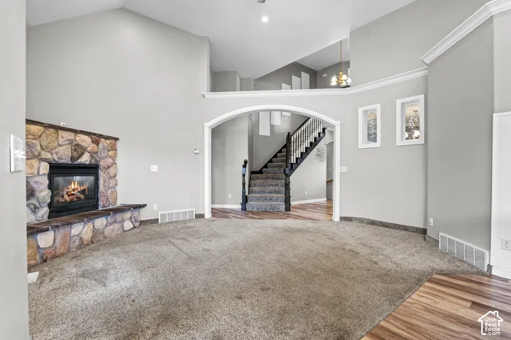 Spacious living area featuring a stone fireplace with hearth seating, vaulted ceilings, and plush carpeting