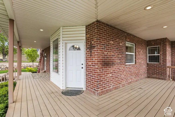 Expansive covered porch featuring wood-finish decking, recessed lighting, and brick exterior walls