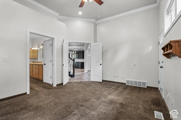 Carpeted room featuring high ceilings, white crown molding, and recessed lighting