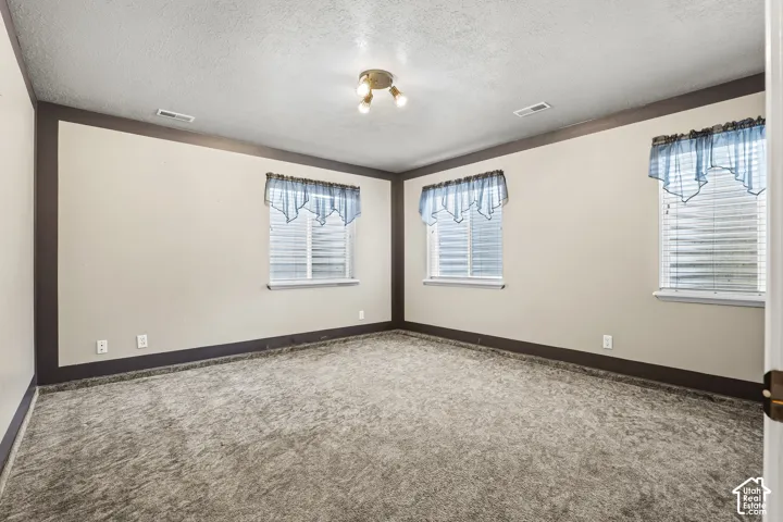 Carpeted room with multiple windows featuring blinds