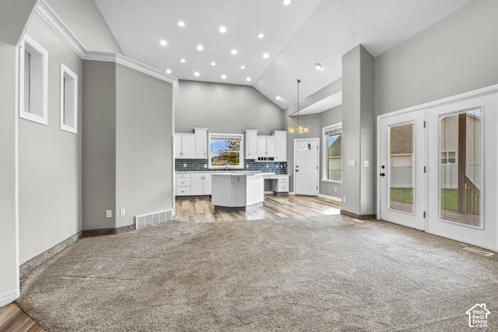 Spacious living area featuring vaulted ceilings, recessed lighting, and soft gray carpeting