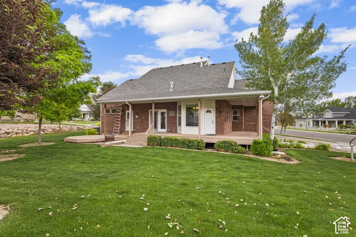 Rear exterior with brick facade and a covered wood deck
