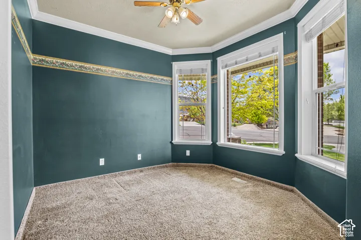 Room featuring a bay window, wall-to-wall carpeting, and a ceiling fan with integrated lighting