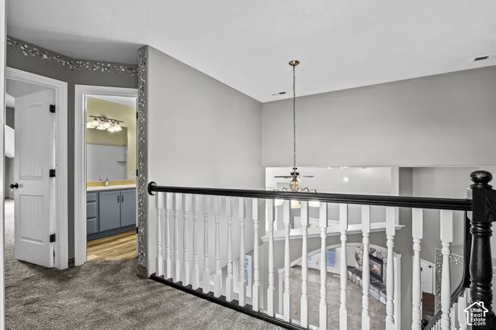 Carpeted hallway with white interior doors, a decorative wall border, and a black and white staircase railing
