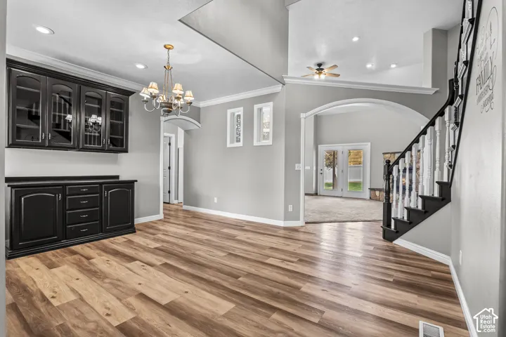Spacious interior featuring wood-finish flooring, a built-in black cabinetry unit with glass fronts, and a decorative chandelier