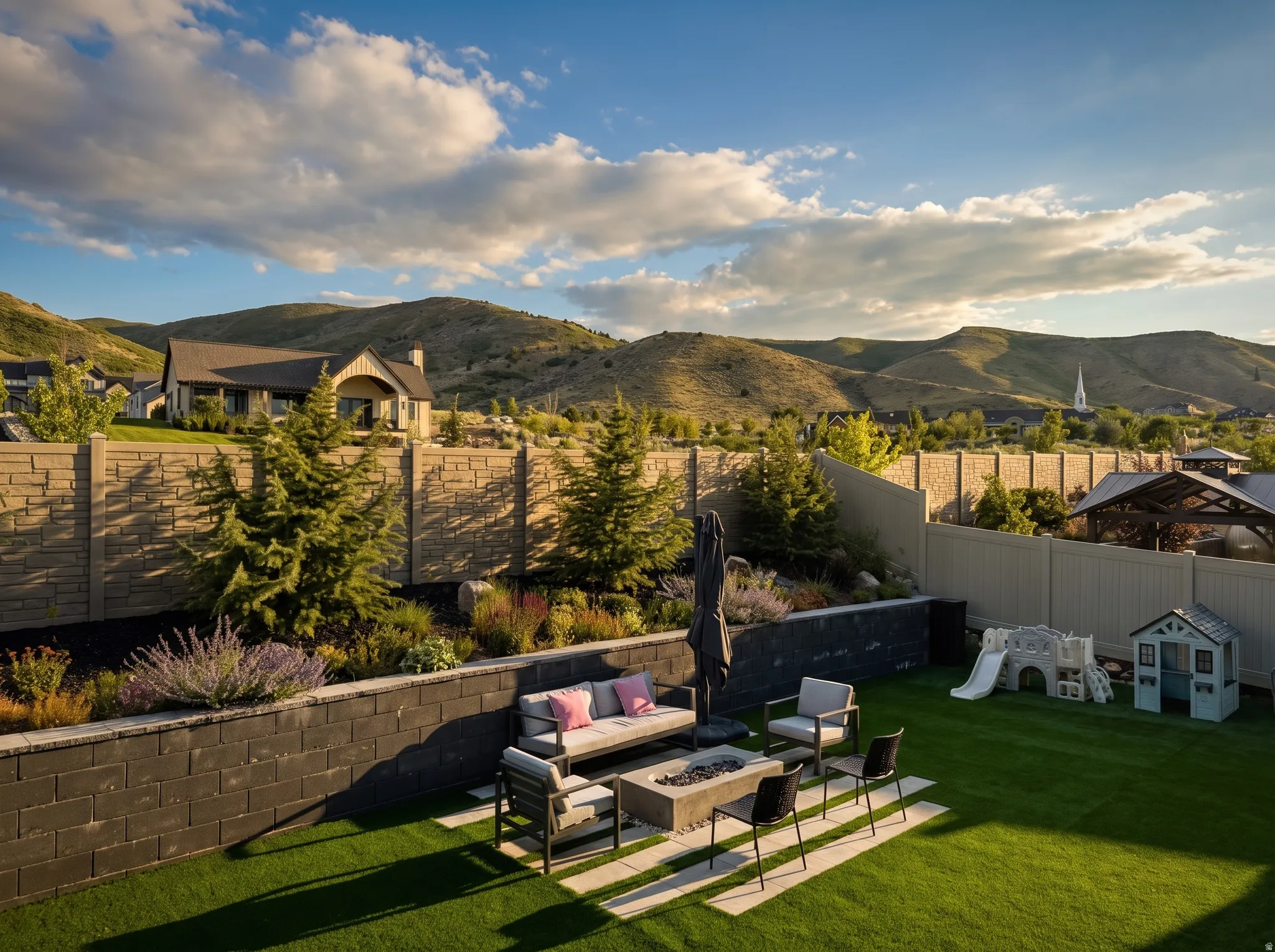 Spacious backyard featuring a manicured lawn, a fire pit area with stone pavers, and tiered landscaping