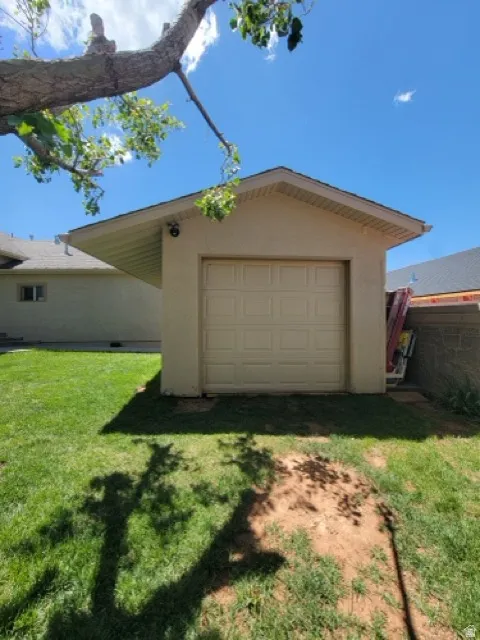 Single-car garage with a paneled door, stucco exterior, and a gabled roofline