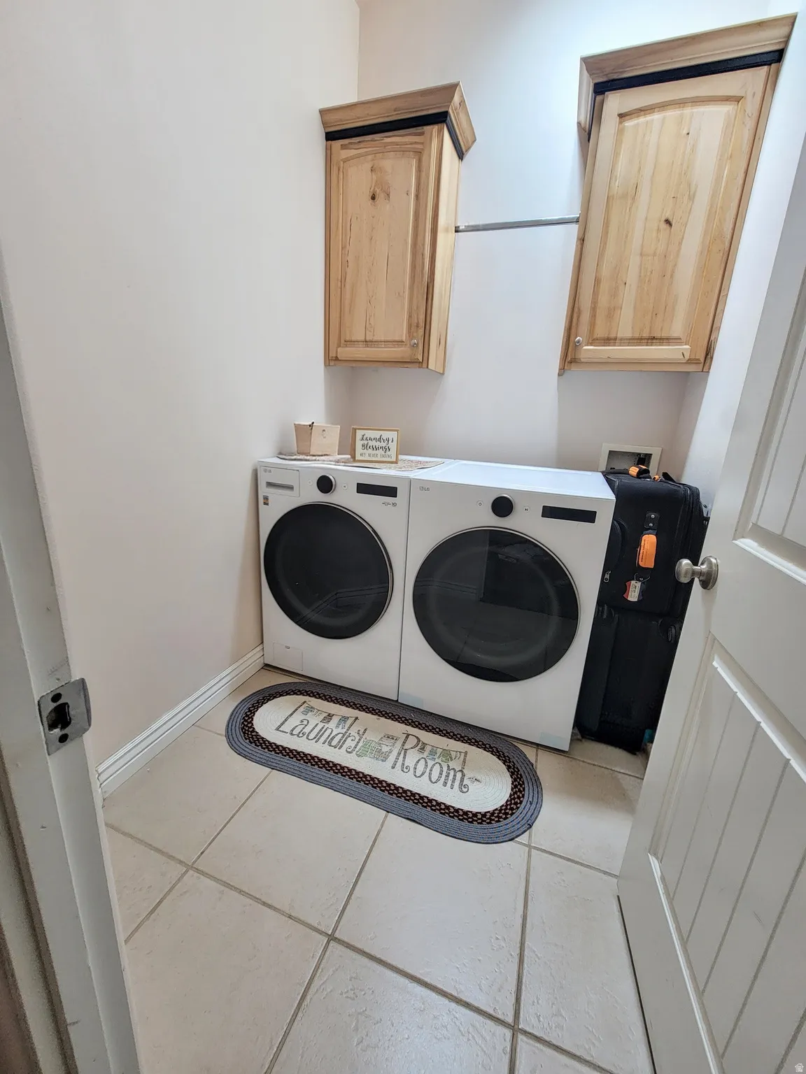 Dedicated laundry area featuring light-toned cabinetry, a hanging rod, and tile flooring