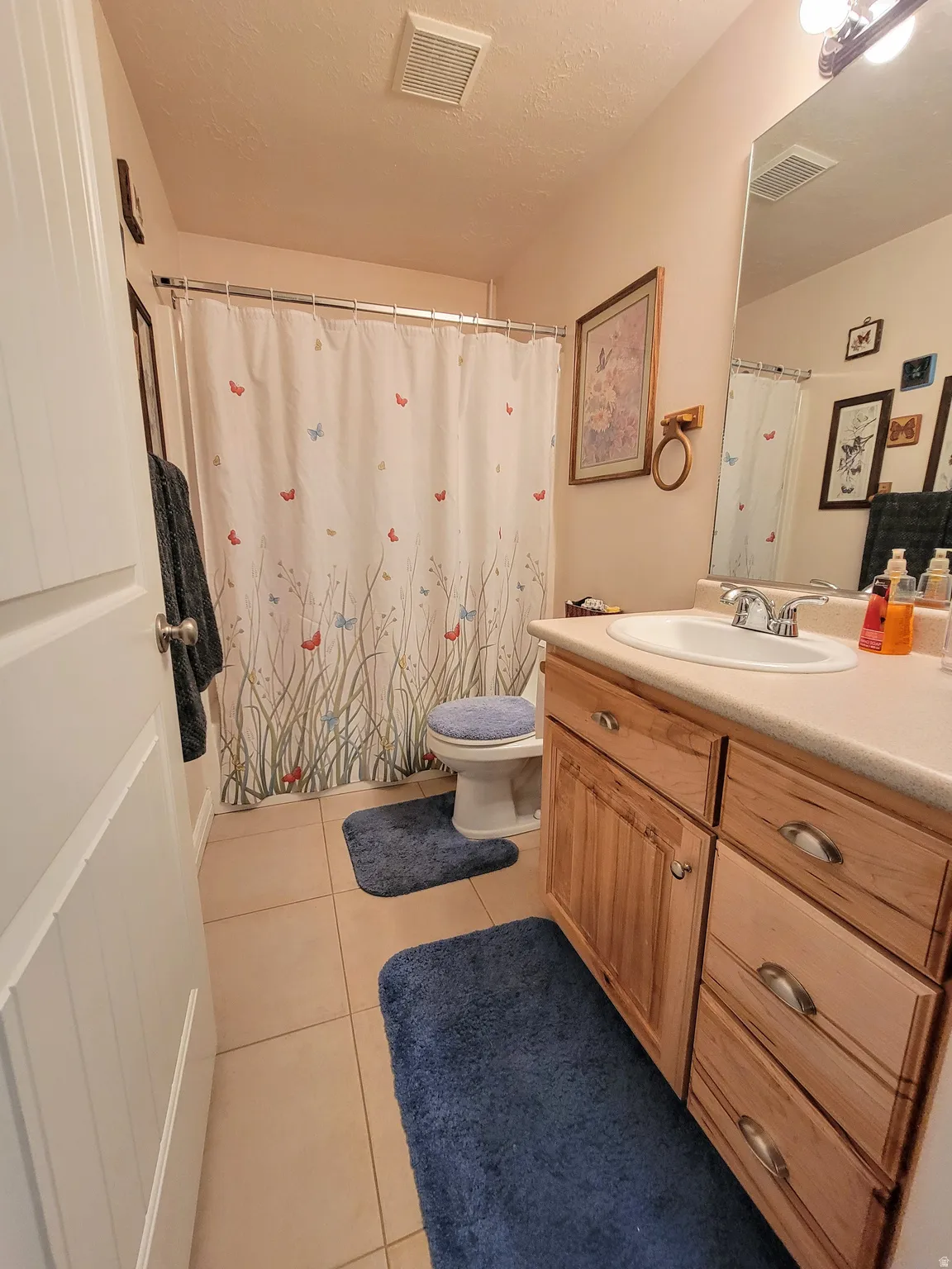 Full bathroom featuring a single vanity with wood-finish cabinetry, a built-in sink, and a framed mirror