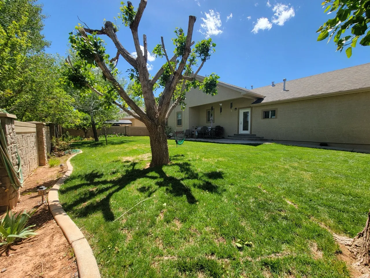 Expansive green lawn with mature trees and a stone-clad perimeter wall