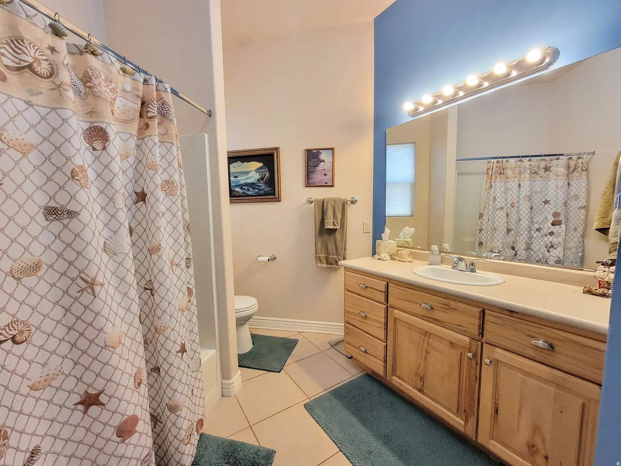 Bathroom featuring a single vanity with wood-finish cabinetry, a large mirror, and a shower-tub combination