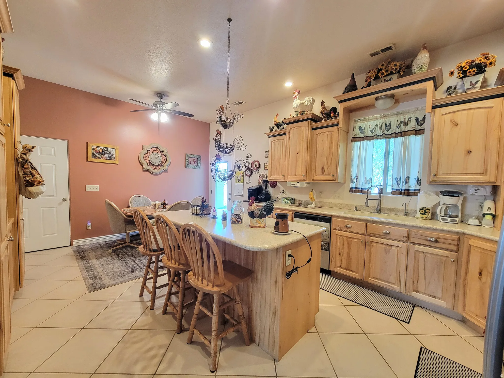Kitchen featuring light wood cabinetry, a central island with bar seating, and tile flooring