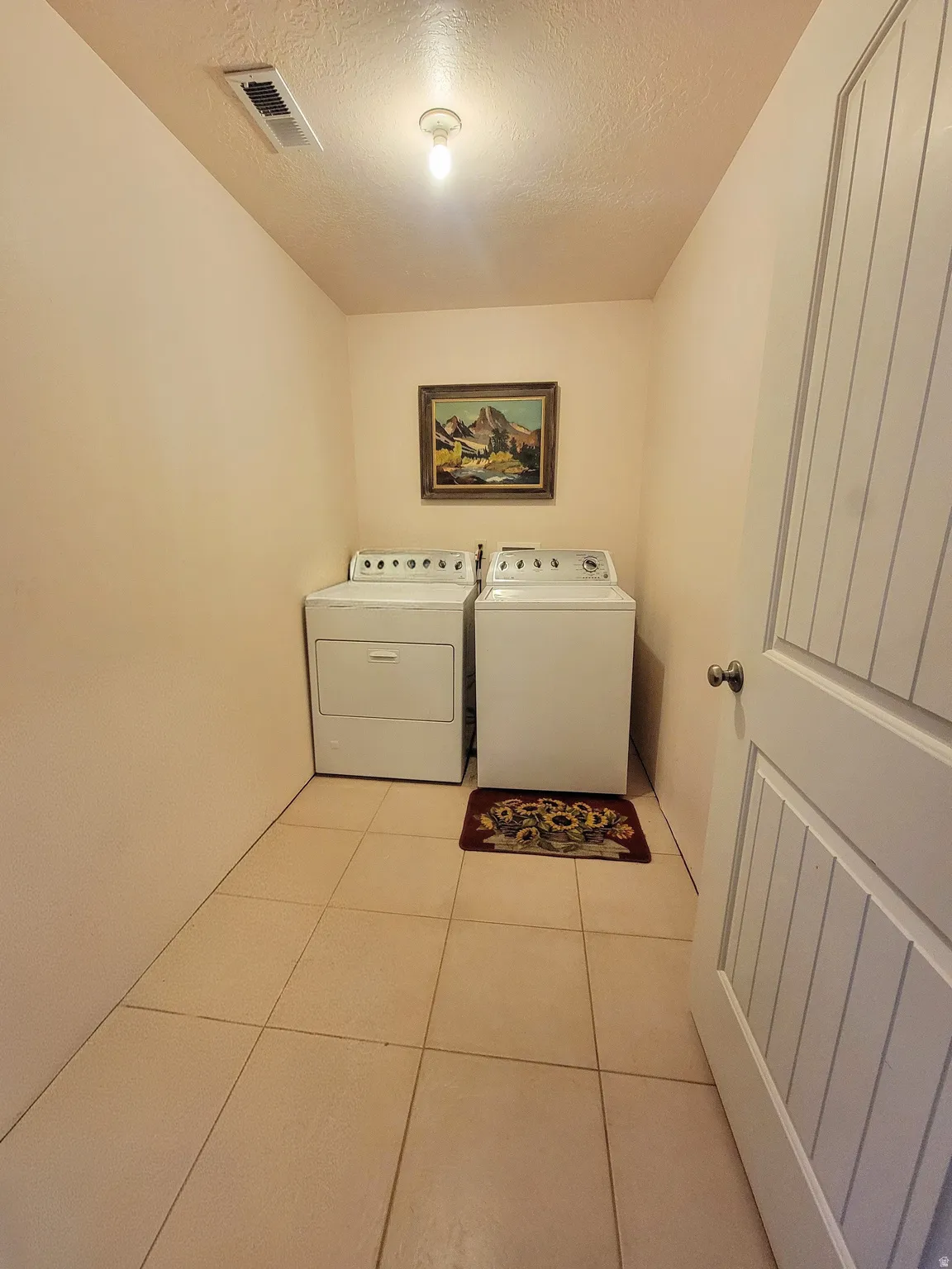 Ceramic tile flooring, neutral wall tones, and a white paneled door
