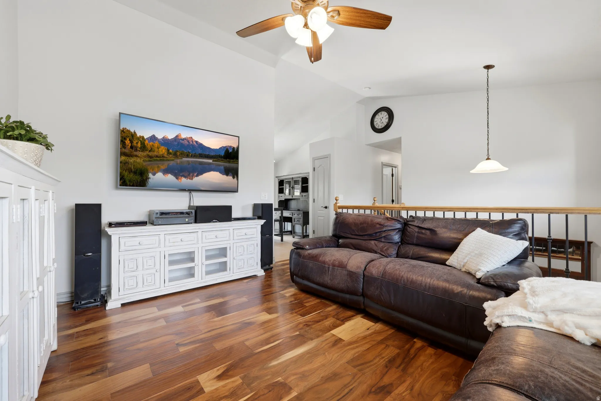 living area featuring vaulted ceilings, wood-finish flooring, contrasting metal and wood railing.