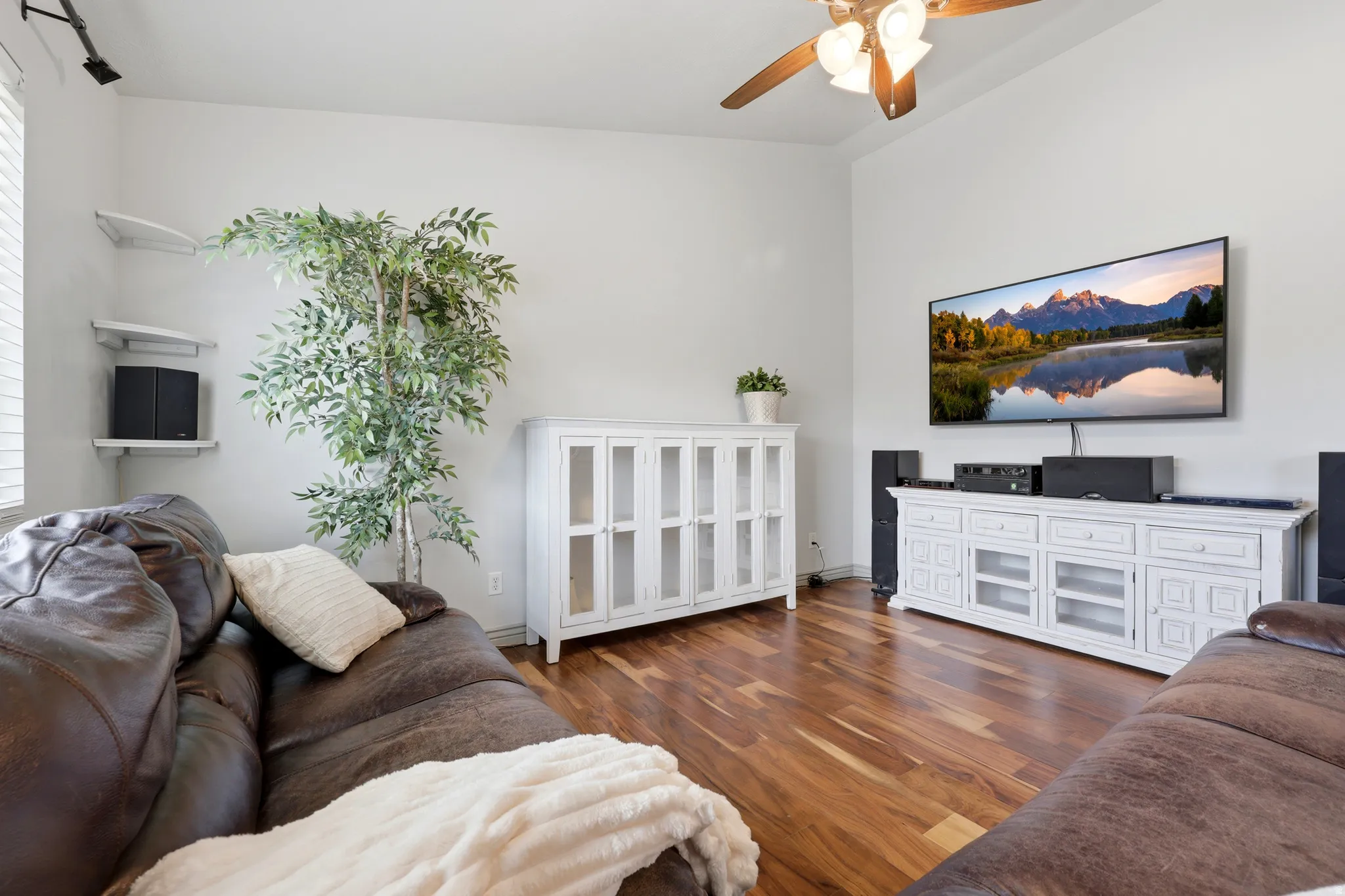 Living space featuring high ceilings, wood-finish flooring, a ceiling fan with integrated lighting