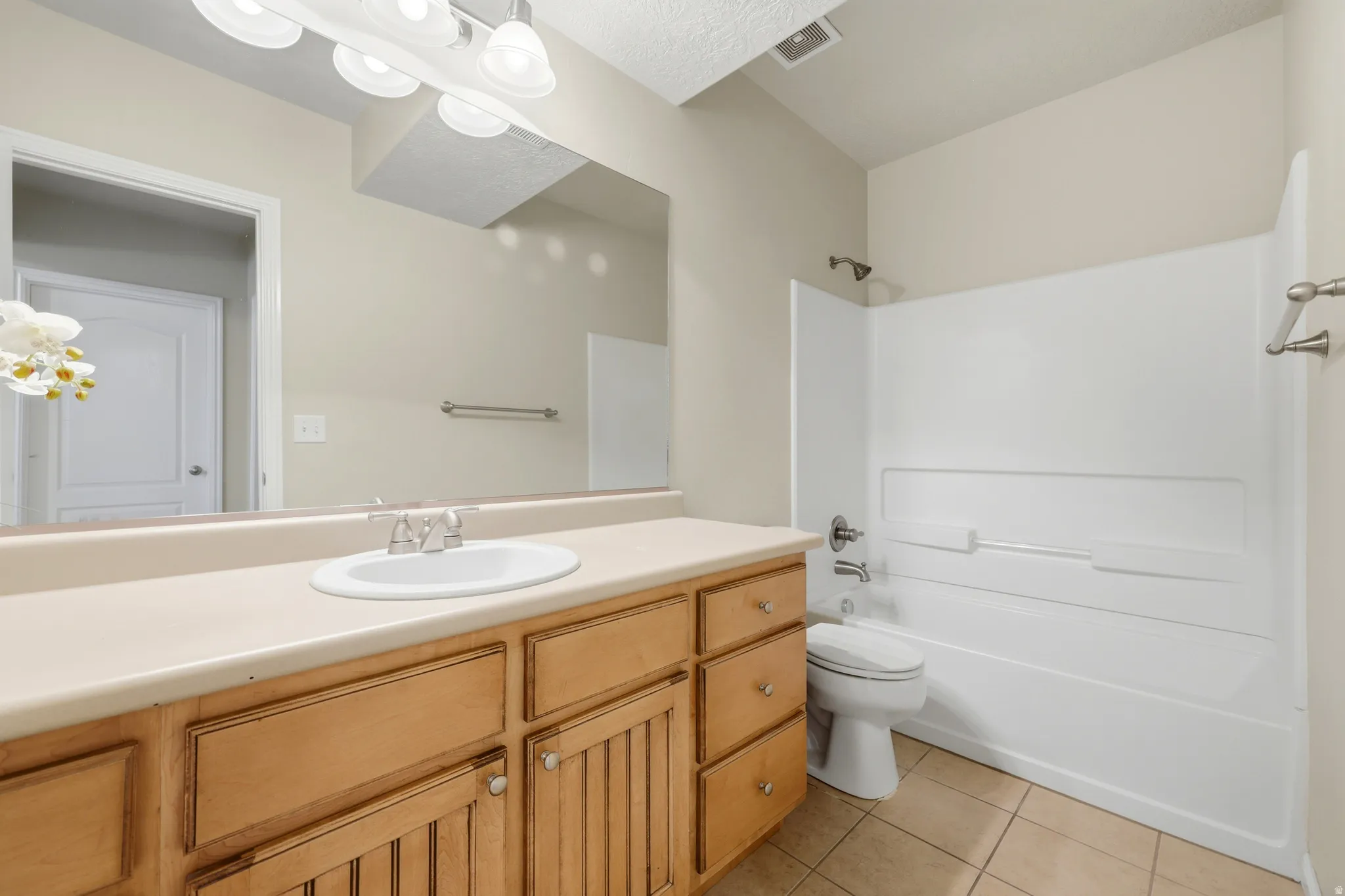 Bathroom featuring a wood-finish vanity with a light-colored countertop and integrated sink