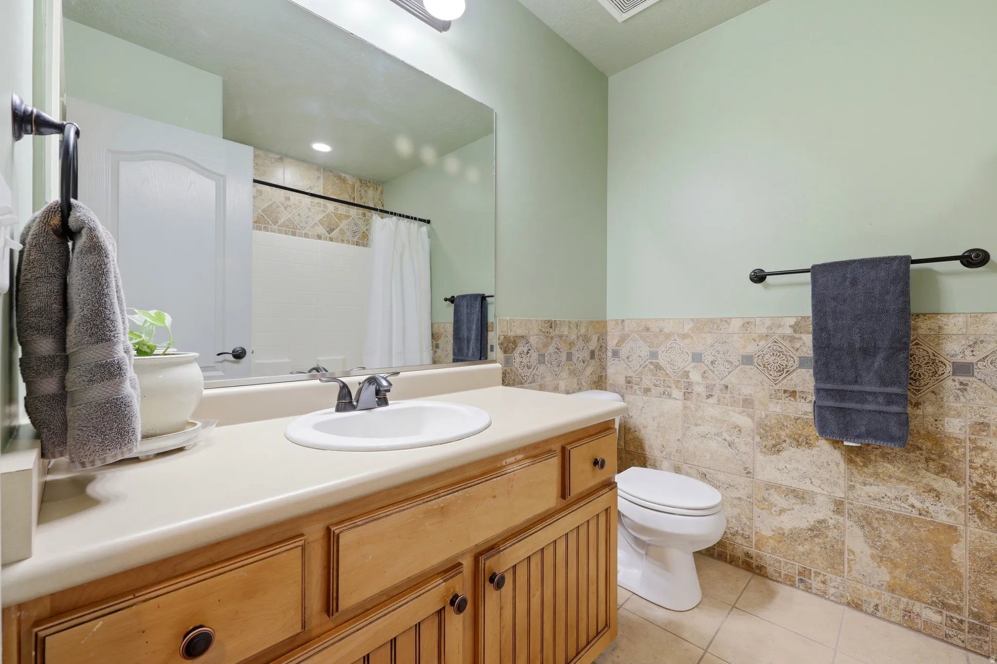 Bathroom vanity featuring a wood-finish cabinet, integrated sink, and light-toned countertop