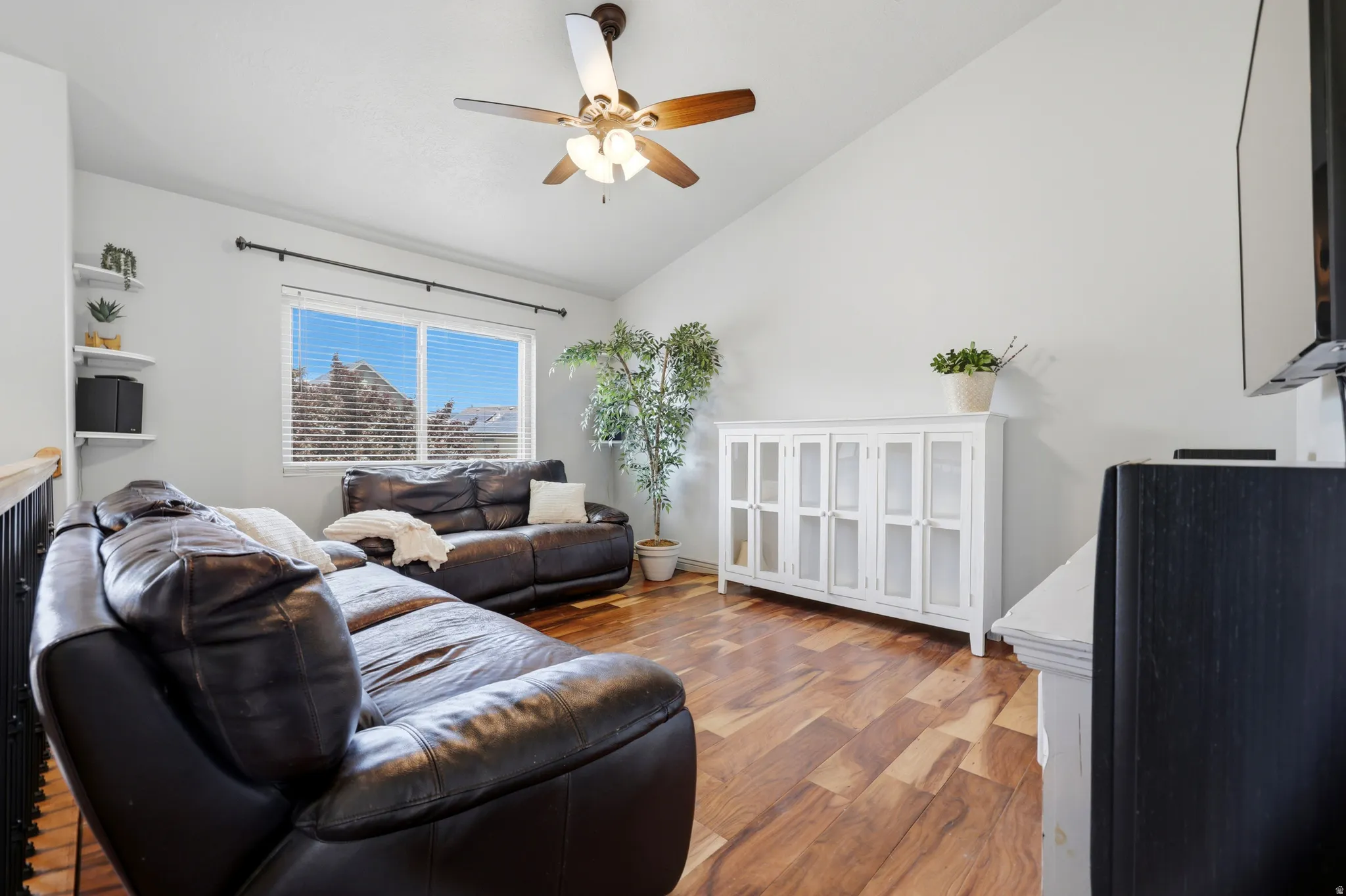 Living area featuring vaulted ceilings, wood-finish flooring, and a ceiling fan