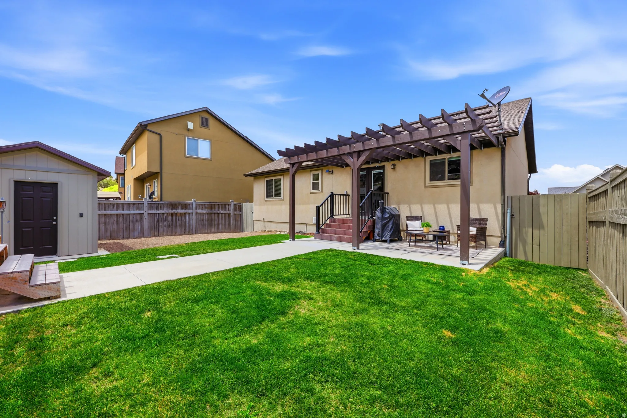 Expansive rear yard featuring a lawn, concrete patio, and a pergola structure