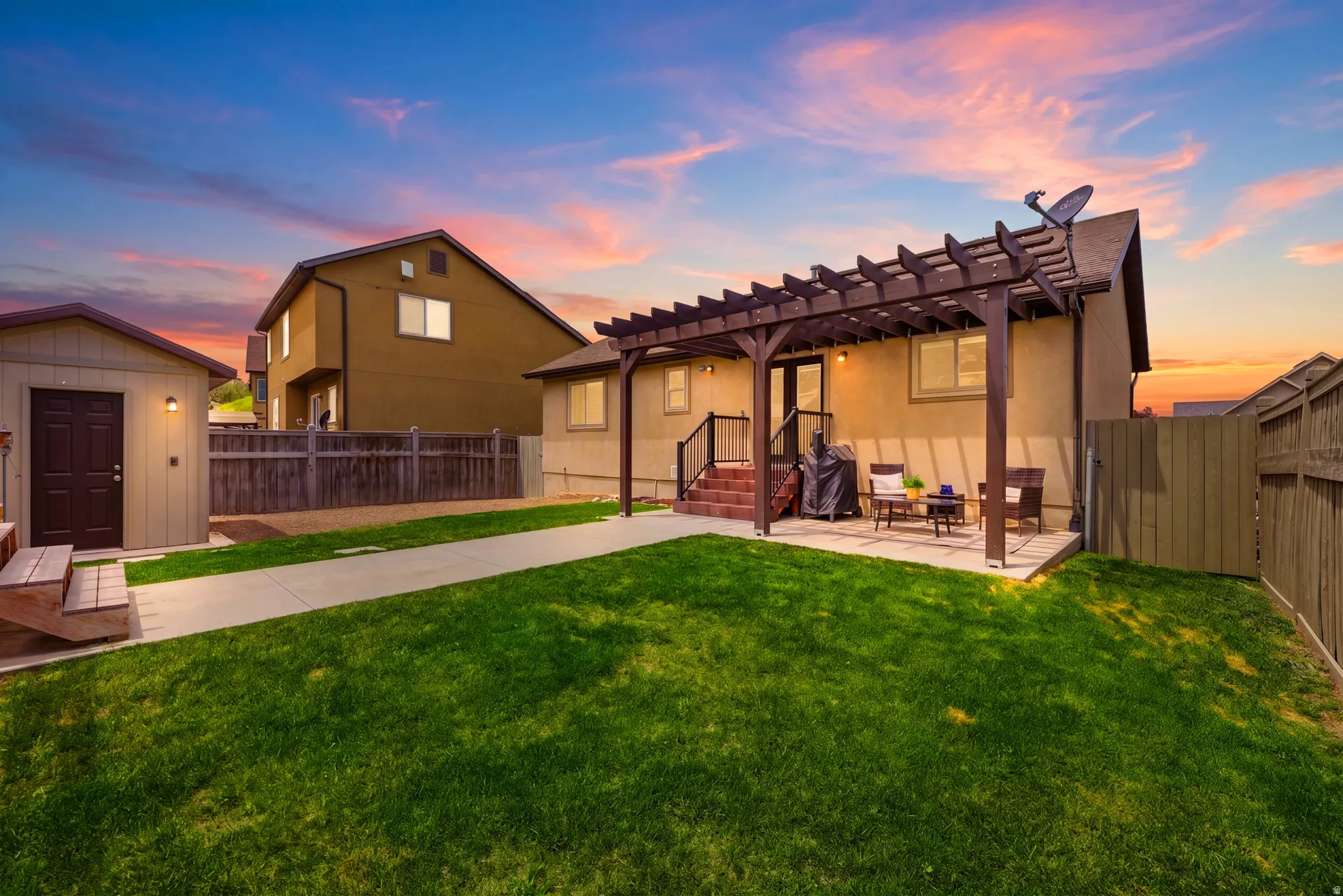 Expansive grassy yard with a concrete pathway leading to a stucco exterior