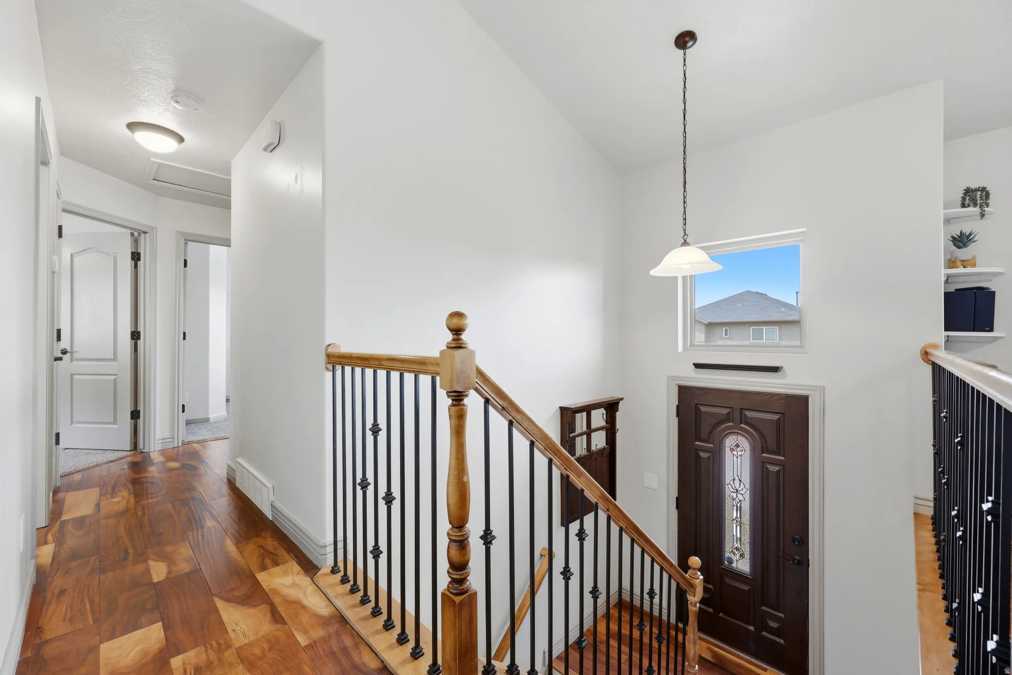 Two-story entryway featuring a dark wood-finish door with decorative glass inlay, an overhead pendant light, and a transom window