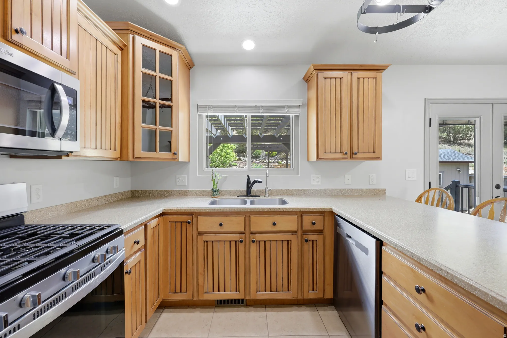 U-shaped kitchen with wood-finish cabinetry, Corian countertops, and stainless steel appliances