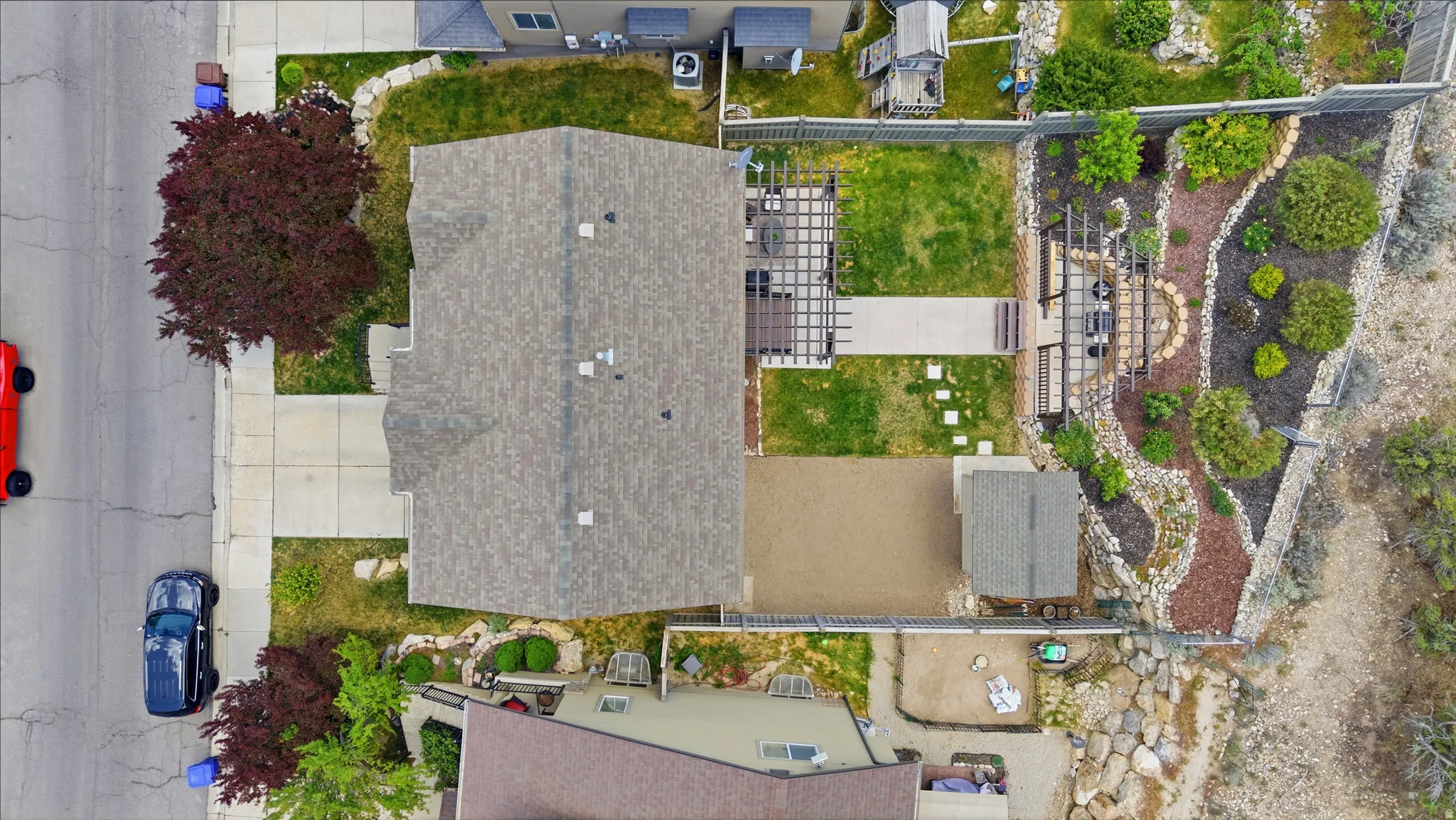 Expansive backyard featuring a manicured lawn, established landscaping, and a wood pergola